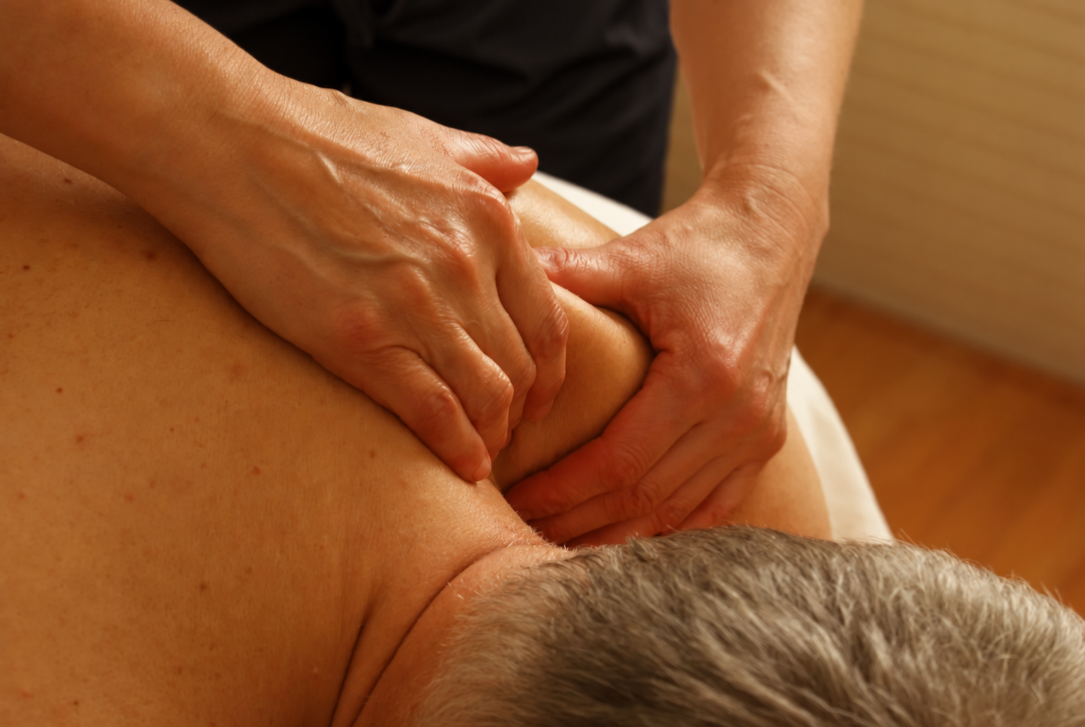 Attentive hands working with a client’s shoulder